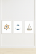 Set of three watercolour nautical wall art prints in white frames on a white wall in a children's bedroom