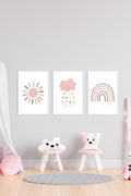 Set of three boho watercolour sun pink heart cloud and rainbow wall art prints in white frames on a grey wall in a girls bedroom